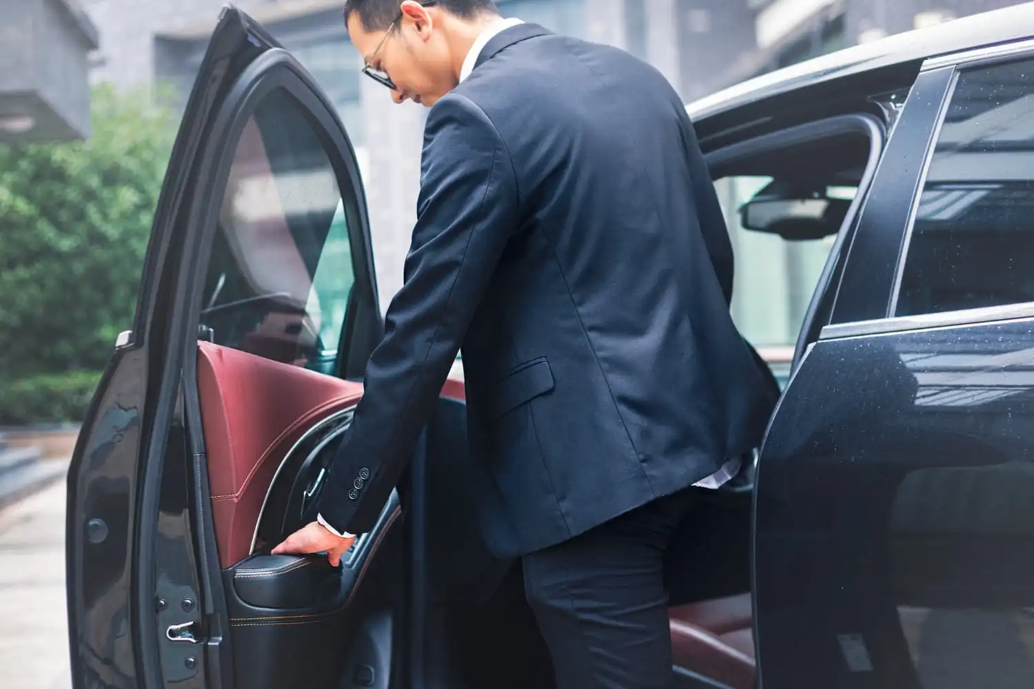 Homme en costume entrant dans une voiture lors d'un convoyage automobile